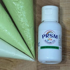 May include: A white bottle of PRSM Sugar Co. Green Apple Liquid Gel with a white cap, beside three green piping bags. The label includes the ingredients and the product name.