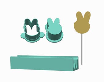 May include: A set of teal plastic tools including two bunny-shaped cookie cutters, a long rectangular teal tray with a grooved channel, and a gold-coloured bunny-shaped topper attached to a thin white stick for decorative use in baking projects.