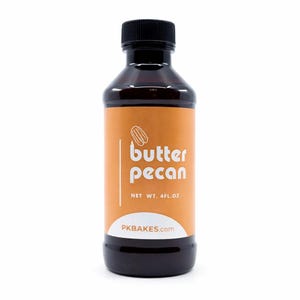 May include: A dark brown plastic bottle with a black screw-top cap, featuring an orange label with a white pecan illustration and the text butter pecan, NET WT. 4FL.OZ, and PKBAKES.com printed in white and orange lettering on the front.