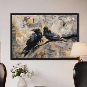 May include: Two black ravens perched on a branch in a painting with a gold and gray abstract background. The painting is framed in black and hanging on a white wall. The wall is decorated with two chairs, a table, a vase with white flowers, and a book. The chairs are upholstered in dark gray fabric and have a high back. The table is made of dark wood and has a drawer. The vase is made of white ceramic and is filled with white flowers. The book is brown and has a white spine.