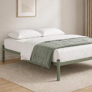 May include: A contemporary bed frame with a sage green metal base. The bed is made up with white bedding, including a duvet and pillows, and a sage green throw. The bed sits on a neutral-coloured rug.