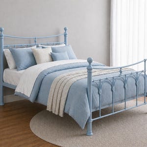 May include: A pale blue metal bed frame with a matching headboard and footboard. The bed is made up with blue and white bedding, including pillows and a blanket. The bed is on a light grey rug.