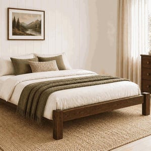 May include: A wooden bed frame with a white comforter, olive green throw blanket, and decorative pillows. The room features a framed landscape painting, a wooden dresser, and a woven rug. The bed frame is approximately 79 inches long.