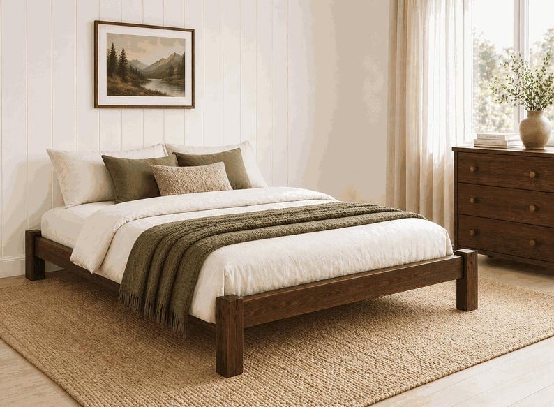 May include: A wooden bed frame with a white comforter, olive green throw blanket, and decorative pillows. The room features a framed landscape painting, a wooden dresser, and a woven rug. The bed frame is approximately 79 inches long.