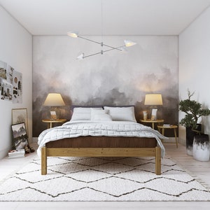 May include: A bedroom with a wooden bed frame, white bedding, and a white rug. The bedroom has a grey and white abstract wall mural, two bedside tables with lamps, and a potted plant.