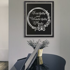 May include: A black framed print with a white floral wreath and the text "Fearfully and Wonderfully Made" on a black background.