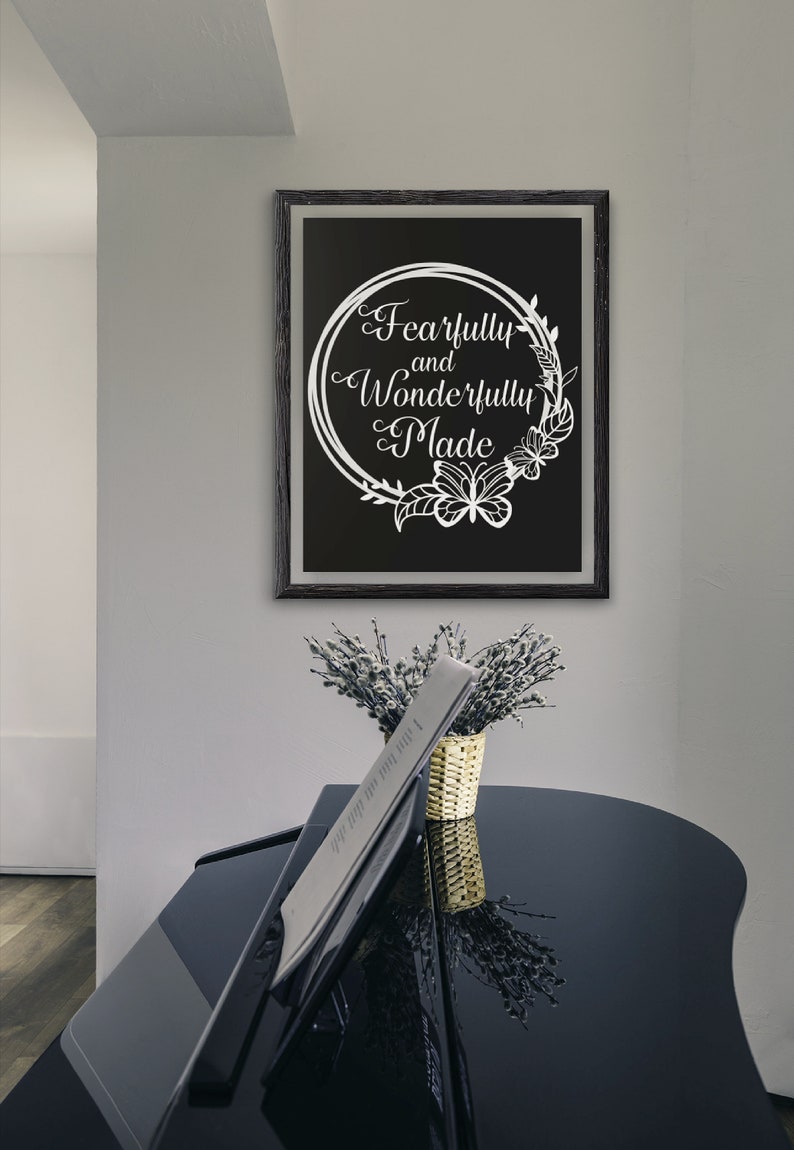 May include: A black framed print with a white floral wreath and the text "Fearfully and Wonderfully Made" on a black background.