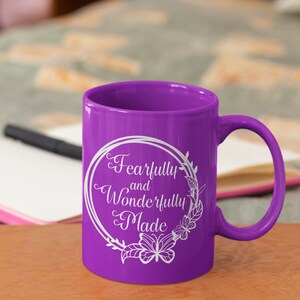 May include: Purple ceramic mug with a white design that says "Fearfully and Wonderfully Made" in a circle with floral accents and butterflies.