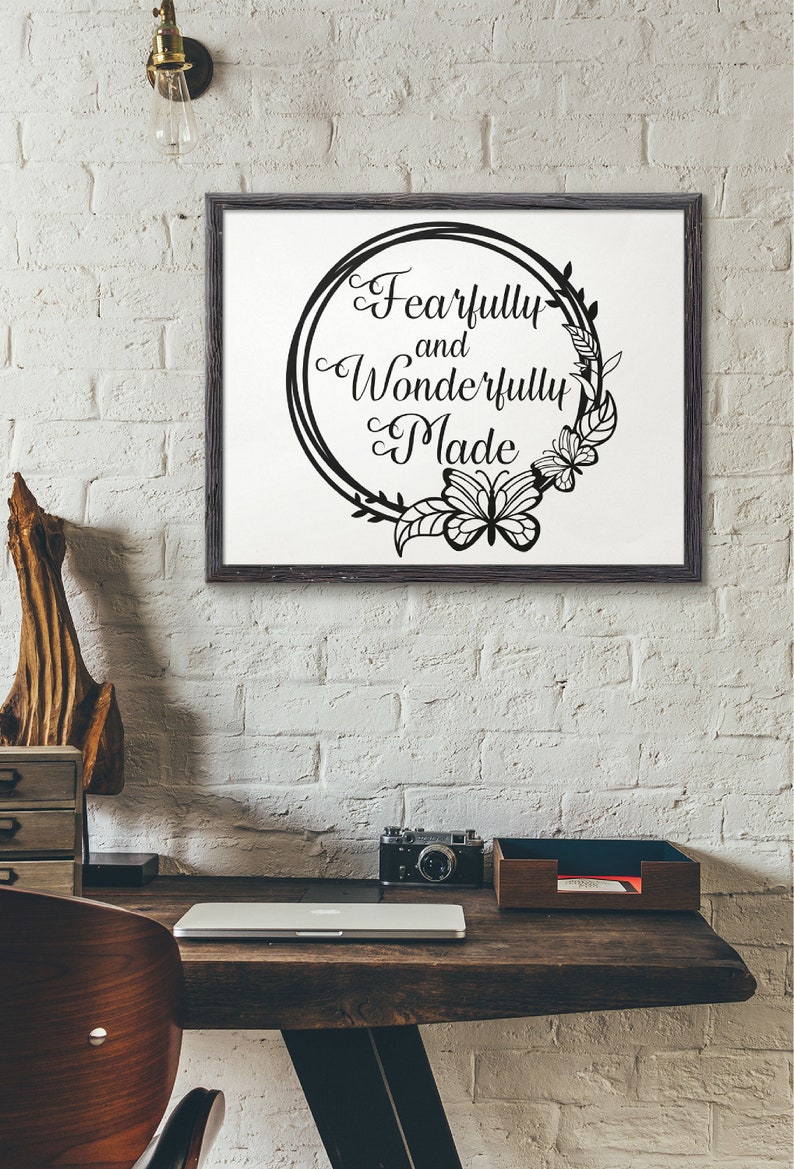 May include: A black and white framed print with a floral wreath and butterfly design. The text inside the wreath reads "Fearfully and Wonderfully Made".