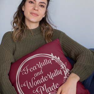 May include: A maroon throw pillow with a white floral wreath design and the text "Fearfully and Wonderfully Made".