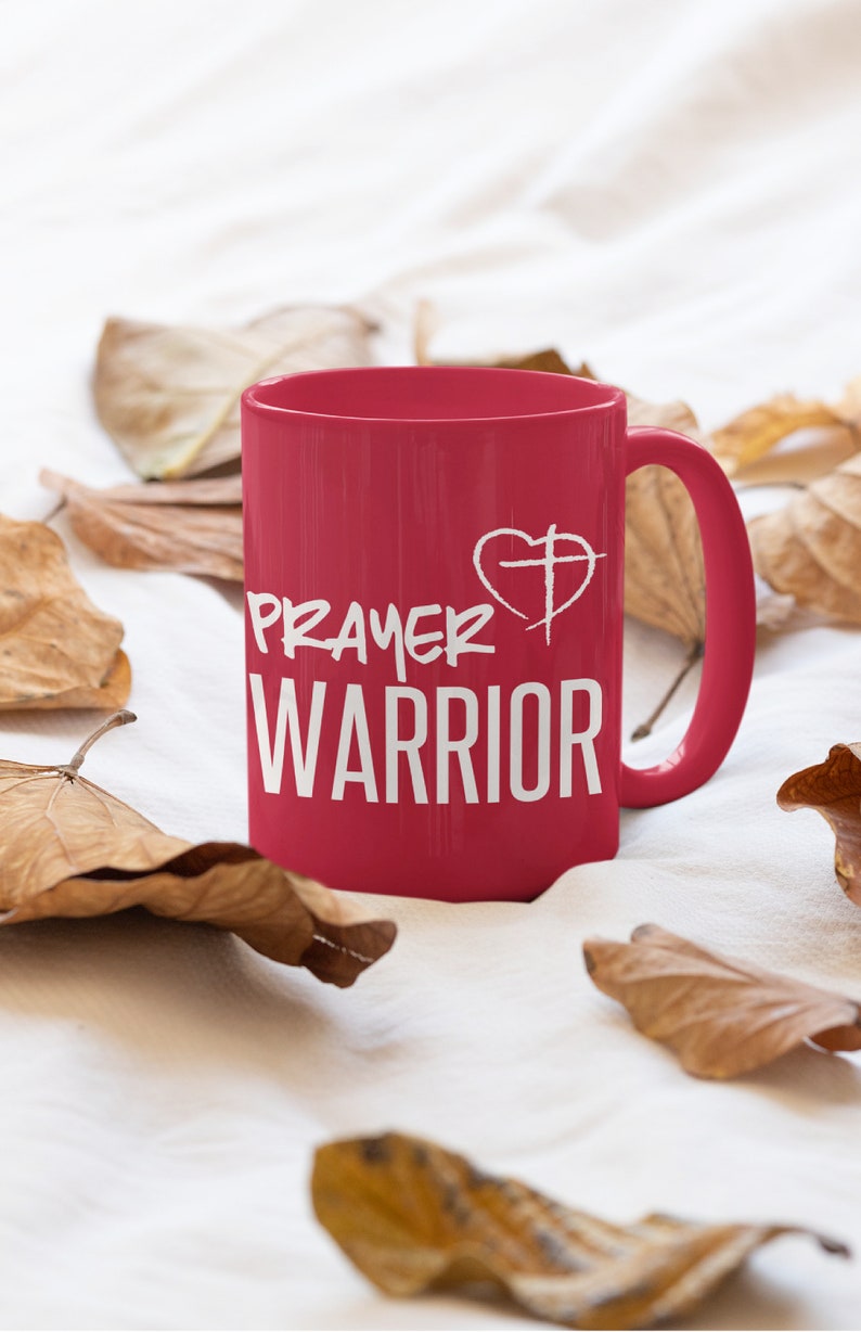 K&ouml;nnte beinhalten: Eine rote Keramiktasse mit einem wei&szlig;en Design, auf dem "Prayer Warrior" mit einem Herz- und Kreuzsymbol steht.
