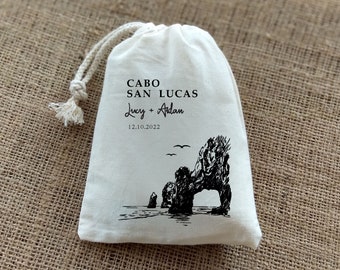 Puede incluir: Bolsa de algodón blanco con cordón de ajuste, con texto negro y una ilustración en blanco y negro de una formación rocosa con un arco. El texto dice "Cabo San Lucas Lucy + Aidan 12.10.2022".