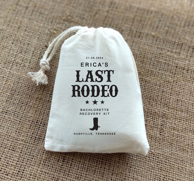 May include: White drawstring bag with black text that reads "Erica's Last Rodeo" with three stars below the text. The text "Bachelorette Recovery Kit" is below the stars. A black boot icon is below the text and the text "Nashville, Tennessee" is below the boot icon. The date "21.09.2024" is at the top of the bag.