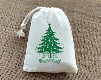 May include: A white drawstring gift bag with a green Christmas tree design. The tree is decorated with ornaments and topped with a star. The words "A Merry Christmas" are printed on a banner below the tree.