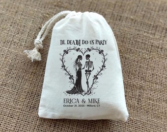 May include: A cream-colored drawstring bag with a black graphic of two skeletons inside a heart-shaped floral wreath. The text "TIL DEATH DO US PARTY" is above the graphic, with "ERICA & MIKE" and a date below.