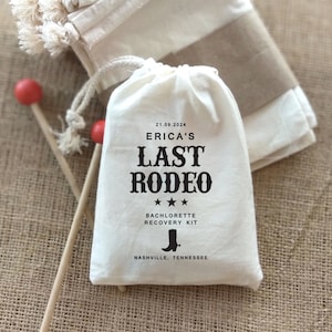 May include: White cotton drawstring bag with black text that reads "21.09.2024 Erica's Last Rodeo *** Bachelorette Recovery Kit Nashville, Tennessee". A cowboy boot icon is printed below the text.