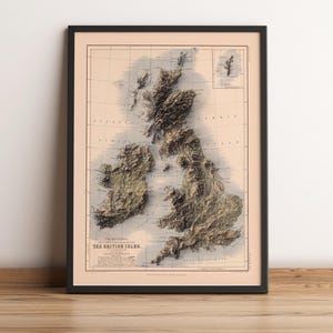 May include: A framed topographical map print titled The Mountains, Lakes, Rivers & Valleys of the British Isles. The map features a beige background with detailed, shaded relief terrain in shades of brown and green, showing the geography of Great Britain and Ireland.