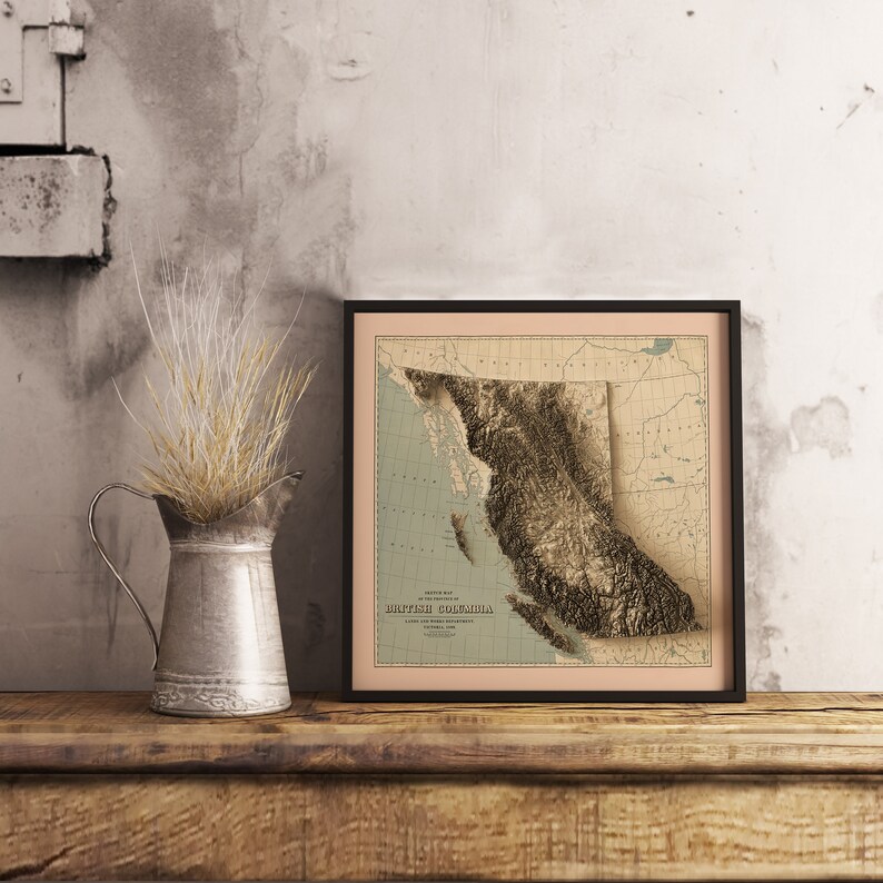Vintage British Columbia shaded relief map in black frame. Realistic terrain art print for home decor, displayed on rustic wooden table