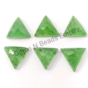 May include: Six triangular, faceted, green gemstones are arranged on a white background. The gemstones have a translucent appearance and are cut into a triangle shape. The text "Gems N Beads Empire" is visible.