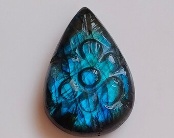 May include: A teardrop-shaped pendant carved with a floral design, made of blue labradorite gemstone.