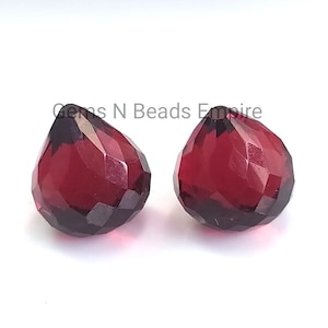 Könnte beinhalten: Zwei tiefrote, facettierte, tropfenförmige Glasperlen. Gems N Beads Empire.