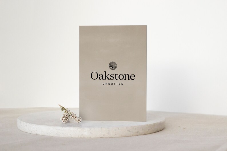May include: A beige card with a black circle logo and the text "Oakstone Creative". The card is sitting on a white marble surface.