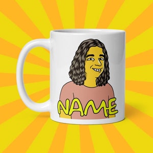 Op de afbeelding: Een witte keramische mok met een cartoonillustratie van een persoon met lang bruin haar en een roze shirt. De tekst "NAME" staat in geel onder de illustratie.
