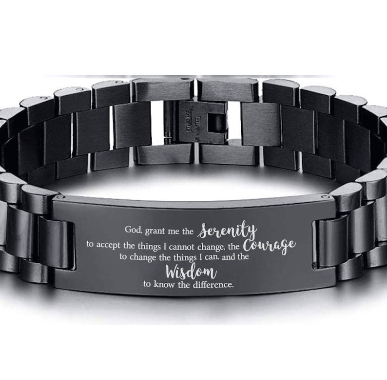 May include: Black stainless steel bracelet with an engraved message: "God, grant me the Serenity to accept the things I cannot change, the Courage to change the things I can, and the Wisdom to know the difference."