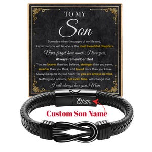 May include: A black leather bracelet with a braided design and a silver-colored infinity knot clasp. The bracelet has a magnetic clasp and includes the text "Ethan" and "Custom Son Name". A decorative card with the text "To My Son" is in the background.