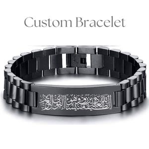 May include: Black stainless steel bracelet with a rectangular center plate featuring white Arabic script. The bracelet has a link design and the text "Custom Bracelet" is above the bracelet.