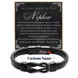 May include: A black leather bracelet with a braided design and a stainless steel clasp. The bracelet features a custom name engraving and an infinity knot design. A card in the background reads "In Loving Memory of Your Nephew."