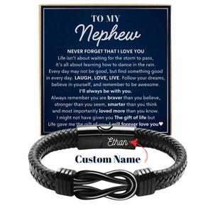 May include: A black braided leather bracelet with a silver-colored infinity symbol clasp. The bracelet is displayed with a card that reads "TO MY Nephew" and a personalized name. The card has a heartfelt message.