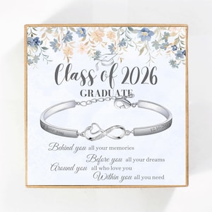 May include: A silver bracelet with an infinity symbol and heart design, presented in a gift box. The box features floral accents and the text "Class of 2026 GRADUATE." The bracelet is engraved with "I love you" and "12.10.2024."