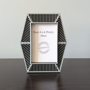 May include: A gray hexagonal picture frame with a black and white striped design. The frame is designed to hold a 4 x 6 inch photo. The text "Your 4 x 6 Photo Here" is printed on the frame.