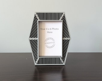 May include: A gray hexagonal picture frame with a black and white striped design. The frame is designed to hold a 4 x 6 inch photo. The text "Your 4 x 6 Photo Here" is printed on the frame.