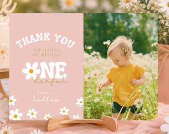 May include: A pink birthday card with the text "Thank You for making my birthday ONE-derful, love Hadley." A photo of a child in a yellow shirt is on the right. A cake with daisy decorations and a vase of flowers are also in the image.