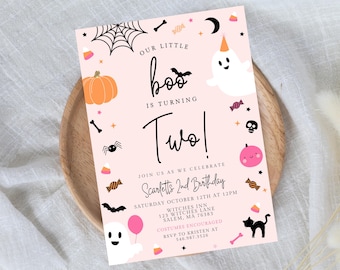 May include: A rectangular birthday invitation card with a light pink background featuring Halloween-themed illustrations including ghosts, a pumpkin, a spider, a bat, a black cat, and candy. The text reads Our Little Boo Is Turning Two!