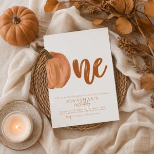 Può includere: Un biglietto d'invito rettangolare bianco con un'illustrazione di zucca ad acquerello e il testo 'one'. Il biglietto include i dettagli per il primo compleanno di Jonathan sabato 12 ottobre 2024 alle 12:00, in 2344 Pumpkin Lane, Cypress, TX.