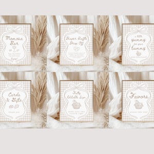 May include: Set of six beige and white signs with text for a baby shower. Each sign has a bow at the top and a decorative border. The signs include text such as "Momosa Bar", "Diaper Raffle Drop Off", and "Favors".
