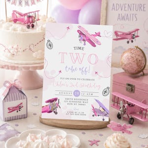May include: A pink and white birthday party scene with a cake, invitation, and decorations. The invitation reads "Time Two Take Off!" and includes airplane illustrations. A small pink airplane cake topper and a decorative globe are also visible.