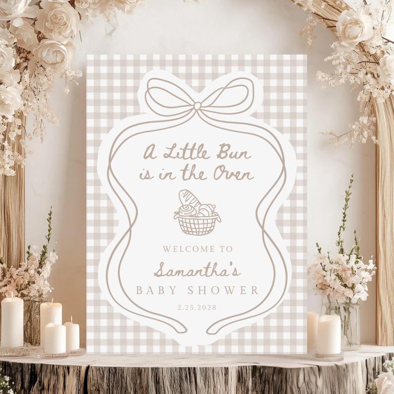 May include: A baby shower sign with a beige and white gingham background. The sign features the text "A Little Bun is in the Oven" and "Welcome to Samantha's Baby Shower 2.25.2028". The sign is decorated with a bow and a basket of bread.