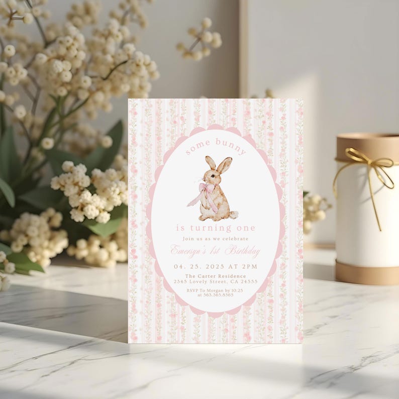 May include: A pastel pink and white invitation card with a bunny illustration. The card features the text "some bunny is turning one" and event details. The design includes floral and striped patterns, perfect for a first birthday celebration.