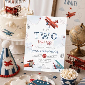 May include: A festive birthday scene with a cake, invitation, and decorations. The invitation reads "Time Two take off!" with airplane illustrations. A cake topper and party hat feature red and blue airplanes. A globe and toy airplanes are also present.