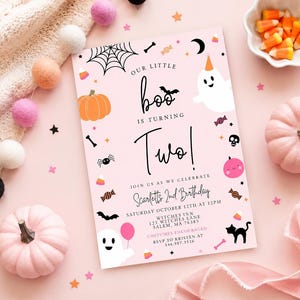 May include: A rectangular light pink birthday invitation card featuring Halloween-themed illustrations including a ghost, pumpkin, spider web, bat, and candy. The text reads: Our little boo is turning two! Join us as we celebrate Scarlett's 2nd birthday.