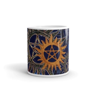 Peut inclure: Une tasse en céramique blanche avec un motif bleu et or représentant un motif répété d'une étoile à cinq branches à l'intérieur d'un soleil éclatant.
