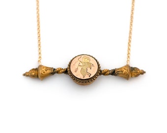 Puede incluir: Un collar de oro con un colgante redondo que presenta un diseño de querubín. El colgante está unido a una barra de oro retorcida con extremos decorativos.