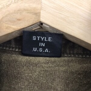 May include: A white ceramic mug with a black handle and the text "But First, Coffee" in a bold, black font. The mug is set against a blurred background, suggesting a cozy setting.