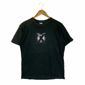 May include: A black short-sleeve t-shirt featuring a centered graphic of a large letter X in a metallic silver finish. Behind the letter X is a circular purple nebula design with small white star-like specks, creating a space-themed visual effect.