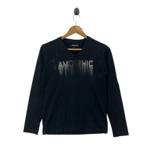 Könnte beinhalten: Schwarzes Langarmshirt mit V-Ausschnitt. Auf dem Shirt steht das Wort "AMORPHIC" in Silber mit einem tropfenden Effekt. Das Shirt hängt an einem Holzkleiderbügel.