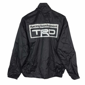 May include: Black nylon jacket with a stand-up collar and a white "Racing Development TRD" logo on the back. The jacket has a full-length zipper and elastic cuffs and hem. A lightweight, sporty outerwear garment.